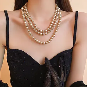 Detailed view of three-strand faux pearl necklace on model wearing a black dress