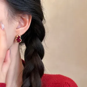 Close-up of a elegant red gourd-shaped stud earring with gold star accents on model's ear