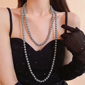 Long multi-layer grey pearl necklace worn with a black sequin dress and lace gloves