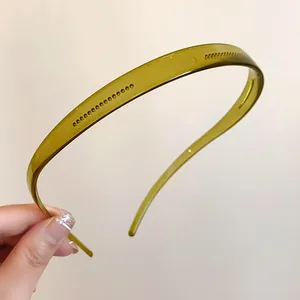 Détail d'un serre-tête en acrylique vert olive montrant sa texture lisse et transparente