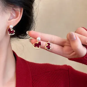 Close-up of elegant red velvet rocking horse and gourd stud earrings with pearls