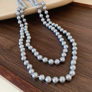 Detailed macro view of elegant long grey silver pearl necklace draped on dark wood