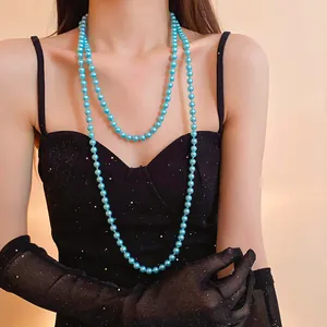 Elegant close-up of a long double-layer light blue pearl necklace on a female model.