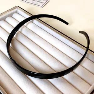Vue détaillée d'un serre-tête noir élégant en acrylique sur un support à bijoux.