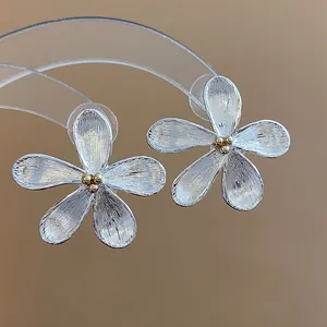 Vue détaillée de boucles d'oreilles fleur en argent brossé avec centre doré élégant