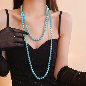 Detailed view of long blue pearl necklace layered on a black cocktail dress