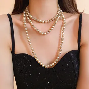 Close-up detail of an elegant multi-layer long pearl necklace on a black glitter dress