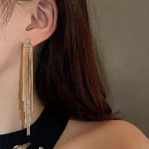 Elegant gold metallic tassel geometric earrings worn by model in minimalist style