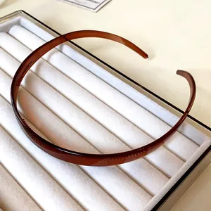 Vue détaillée d'un serre-tête en acrylique marron minimaliste sur un plateau en velours blanc
