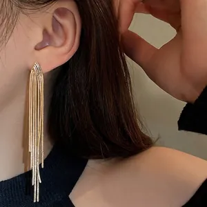 Elegant gold tassel earrings featuring long flowing metal chains on a model