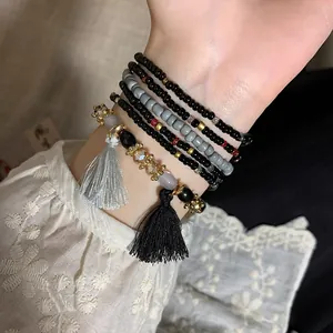 Close-up detail of bohemian multi-layered bead bracelets with tassels shown on wrist