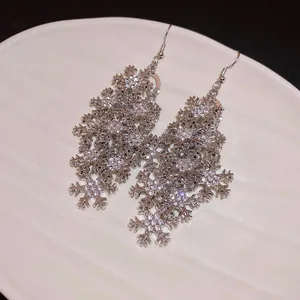 Close-up detail of silver snowflake tassel earrings with brilliant rhinestone inlay