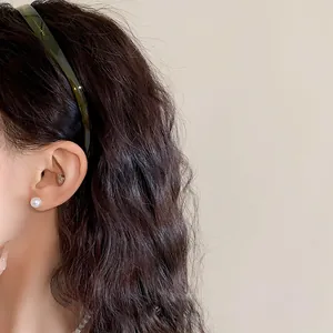 Détail d'un serre-tête ondulé en acrylique vert foncé sur des cheveux ondulés.