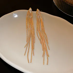 Elegant detailed view of long gold-toned metal fringe tassel earrings displayed on a gray plate