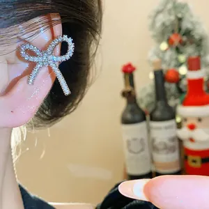 Primo piano di un ear cuff a fiocco in zircone scintillante indossato.