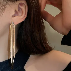 Detail view of gold long tassel earrings worn, showing the metallic fringe texture