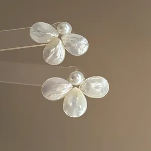 Close-up detail of elegant mother-of-pearl flower stud earrings with central pearl