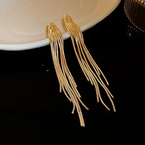 Close-up detail of elegant golden metal long tassel earrings with geometric studs