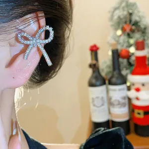 Primo piano di un ear cuff a fiocco con zirconi brillanti indossato sull'orecchio.