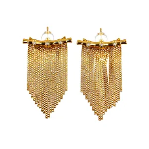 Élégantes boucles d'oreilles pendantes à pompons dorées 14K avec zircons sur fond blanc