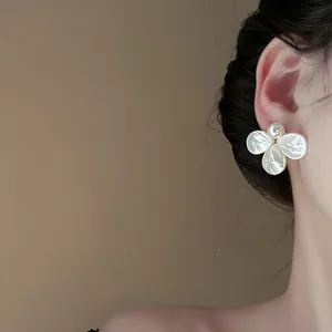 Detailed macro view showing an elegant mother-of-pearl flower earring with pearl on ear