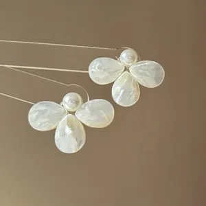 Detailed macro view of mother-of-pearl flower petals and central pearl earrings