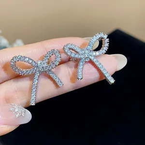 Dettaglio ravvicinato di eleganti orecchini a clip a fiocco argentati con zirconi scintillanti.