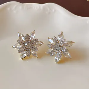 Close-up of crystal snowflake earrings with intricate rhinestone details on a cream plate.