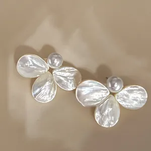 Macro detail of mother-of-pearl flower earrings with central pearls and silver posts