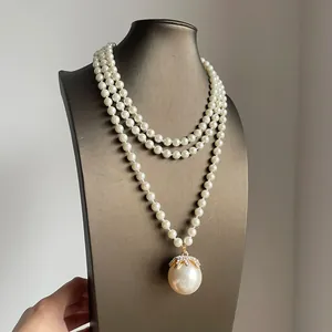 Primo piano di una collana di perle vintage a tre fili con un grande pendente