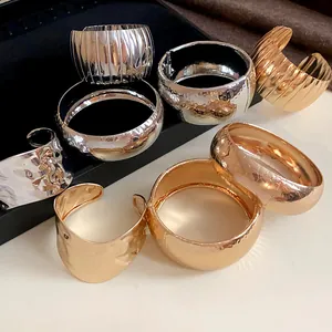 Dettaglio di vari bracciali rigidi in metallo oro e argento con texture martellata