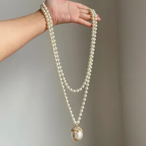 Dettaglio ravvicinato di un'elegante collana di perle a doppio filo con ciondolo