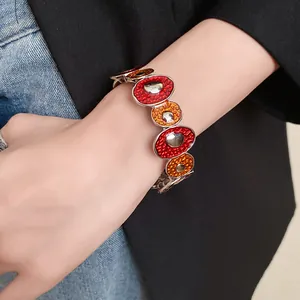 Dettaglio di un bracciale in smalto con cerchi irregolari rossi e arancioni indossato al polso