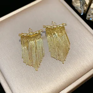 Gros plan de boucles d'oreilles à pampilles dorées avec zircon et franges de chaînes