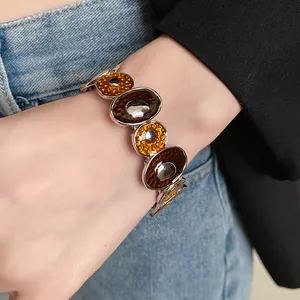 Primo piano di un bracciale vintage in smalto con maglie irregolari indossato al polso.
