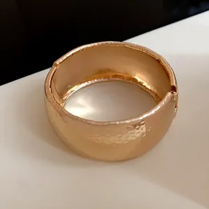 Vista dettagliata del bracciale rigido a cerniera in metallo oro rosa martellato