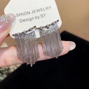 Gros plan de boucles d'oreilles élégantes à pompons avec barres en zircone bambou