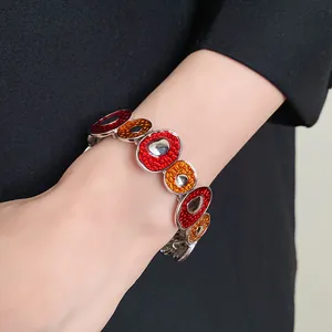 Dettaglio di un bracciale smaltato vintage con maglie circolari irregolari rosse e arancioni