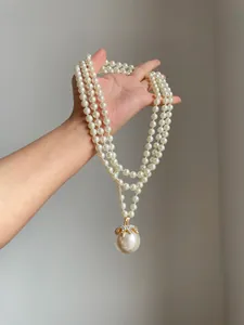 Dettaglio di una collana di perle vintage a più fili con ciondolo di strass lucenti