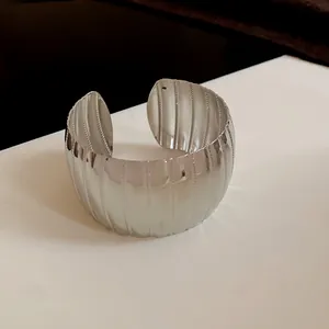 Vista dettagliata di un ampio bracciale rigido in metallo argentato strutturato