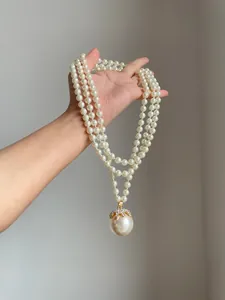 Primo piano di una collana di perle vintage a più fili con un grande pendente di strass.