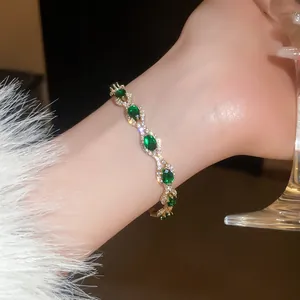 Close-up of vintage gold bracelet with emerald crystals and sparkling diamonds