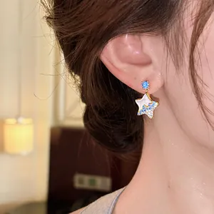 Elegant star stud earring with blue rhinestones shown worn on an ear for detail