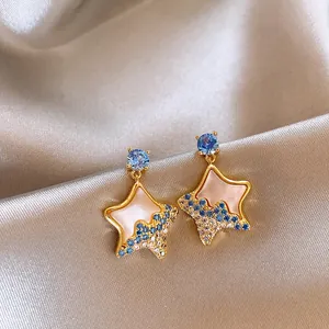 Detailed macro view of star-shaped earrings with blue and white crystals on satin fabric