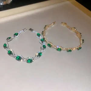 Close-up of gold and silver bracelets with green crystals and sparkling pavé diamonds