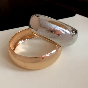Dettaglio ravvicinato di bracciali metallici larghi con trama a pelle di coccodrillo