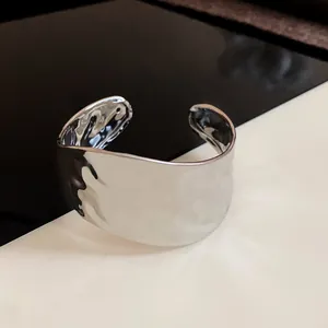 Primo piano del bracciale rigido in metallo martellato argento con trama irregolare