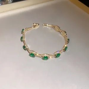 Close-up of a vintage court style gold bracelet with emerald green stones