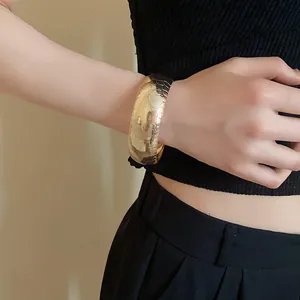 Vista dettagliata di un audace bracciale in metallo dorato con trama a scaglie di serpente.