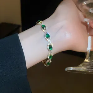 Elegant vintage gold bracelet with oval green gemstones and crystal pavé on female wrist.